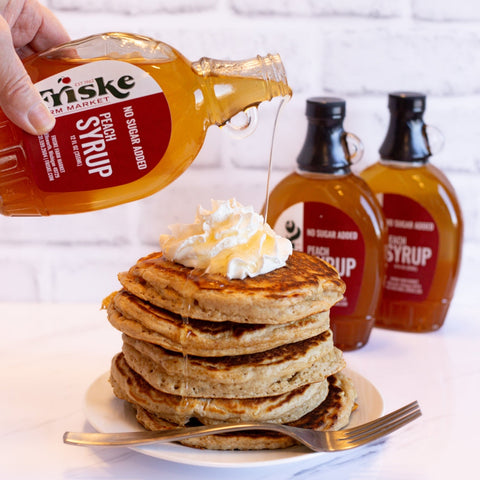 Syrup poured from bottle over stack of pancakes