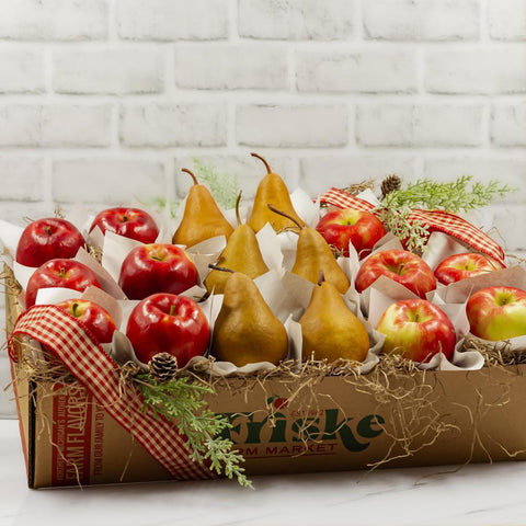 Apples and pears sitting in a Friske gift box. Shown with red checked ribbon, cedar picks, and sitting on tissue paper.
Fresh apples and pears are shipped in this box with paper grass.